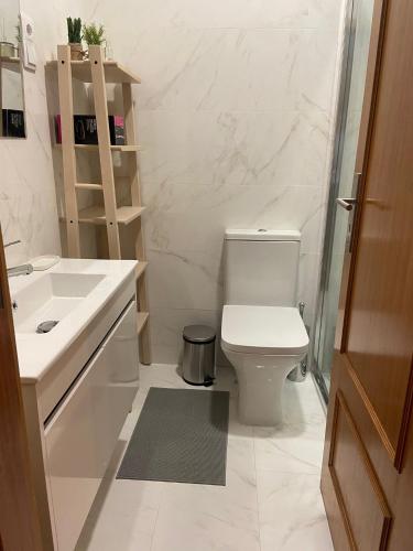 a bathroom with a white toilet and a sink at Apartamento Central in Braga
