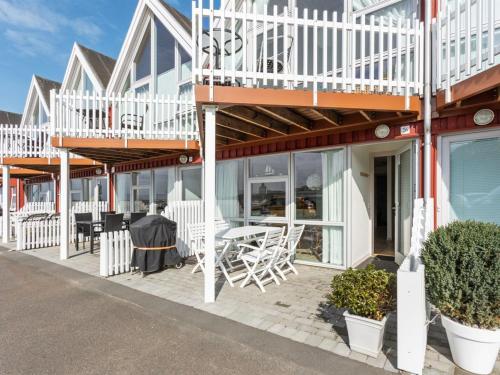 a building with white chairs and tables on a patio at Holiday Home Momo - 10m from the sea in Bornholm by Interhome in Hasle