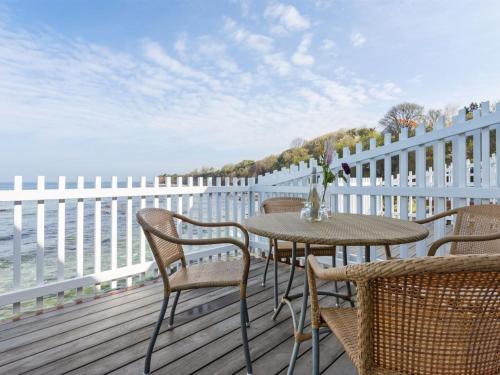 a table and chairs on a deck with the water at Holiday Home Momo - 10m from the sea in Bornholm by Interhome in Hasle