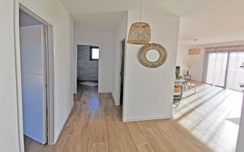 a hallway with white walls and wooden floors and a mirror at Résidence Petra Paolina in Folelli