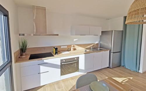 a kitchen with white cabinets and a stainless steel refrigerator at Résidence Petra Paolina in Folelli