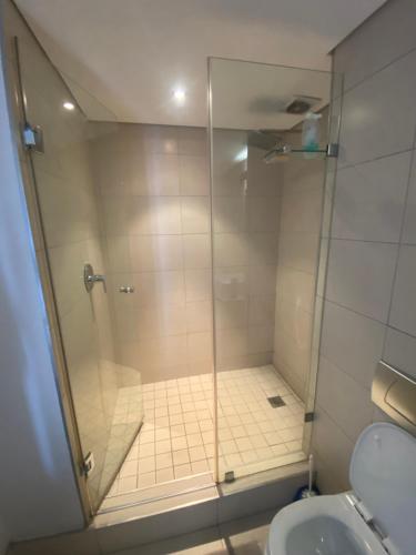 a shower with a glass door next to a toilet at 608 Beacon Rock in Durban