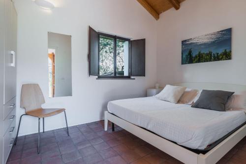 um quarto branco com uma cama e uma cadeira em Terrazze dell'Etna - Country rooms and apartments em Randazzo