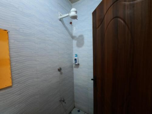 y baño con ducha y pared blanca. en Travelers staycation - 15 Mins to Westlands en Kikuyu