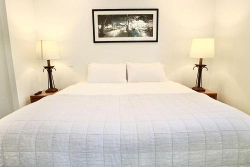 - une chambre avec un grand lit blanc et deux lampes dans l'établissement 617 Hastings Street metres to the beach, à Noosa Heads