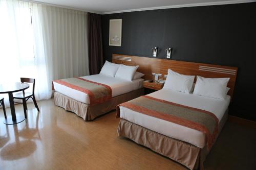 Habitación de hotel con 2 camas y mesa en Alto del Sol Latorre Mejillones, en Mejillones