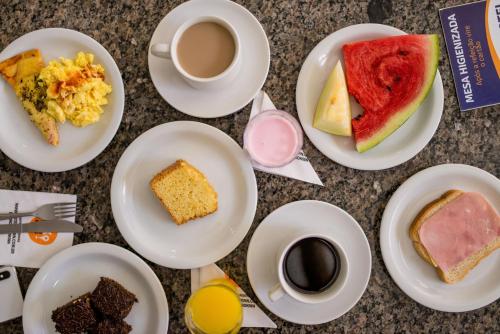 a table with plates of breakfast foods and a cup of coffee at OK Inn Hotel Criciúma in Criciúma