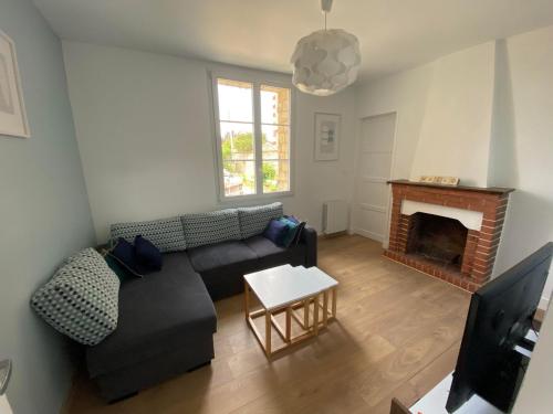 a living room with a couch and a fireplace at Maison cosy en plein coeur de Ouistreham in Ouistreham