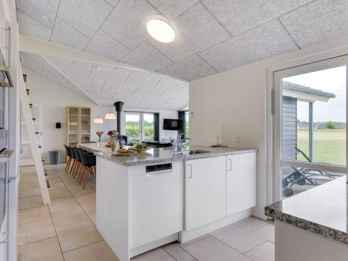 a kitchen with white cabinets and a dining room at Holiday Home Finja - 500m from the sea by Interhome in Neder Lysabild