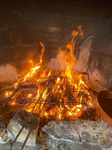 a grill with a lot of fire in a fireplace at El Mirador de la Sierra Y Casa Rosmari in Urueñas