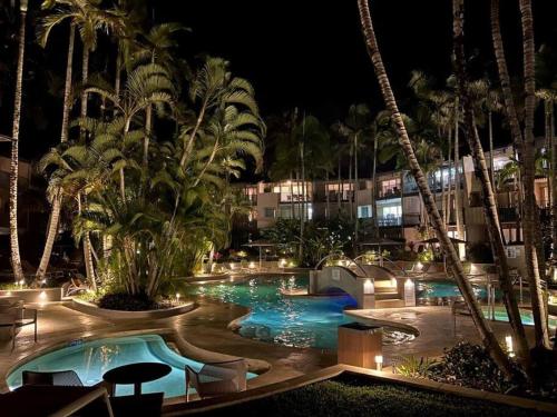 una piscina del complejo por la noche con palmeras y edificios en 124 Hastings Street 2 bedroom walk to the beach, en Noosa Heads