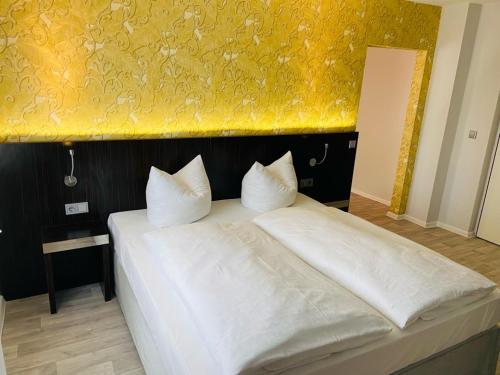 a bedroom with a white bed with a yellow wall at Hotel 22 in Dessau