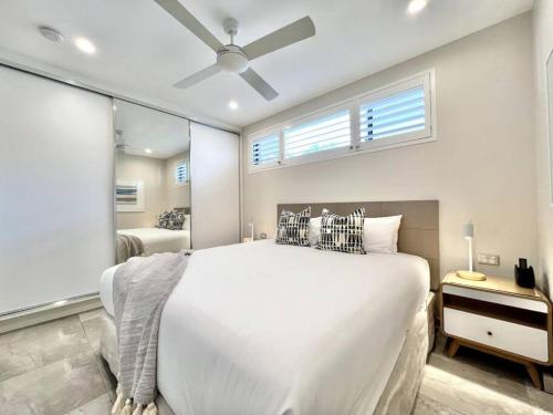 a bedroom with a large white bed and a window at 6Apt Beautifully renovated on Hastings Street in Noosa Heads