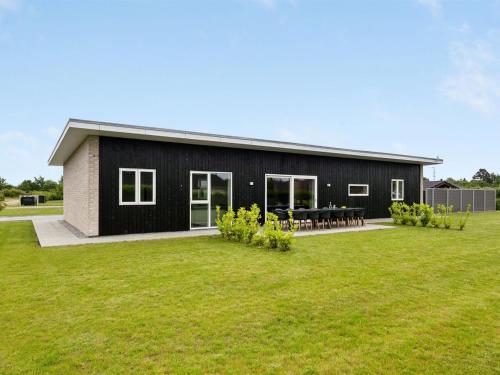 a black house with a large grass yard at Holiday Home Holmsten - 1km from the sea in SE Jutland by Interhome in Neder Lysabild