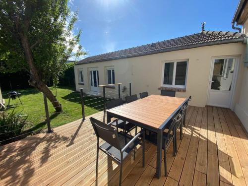 une terrasse en bois avec une table et des chaises dessus dans l'établissement Maison cosy en plein coeur de Ouistreham, à Ouistreham
