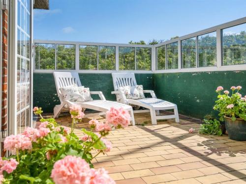 two white chairs sitting on a patio with pink flowers at Holiday Home Mattias - 100m from the sea in Western Jutland by Interhome in Fanø