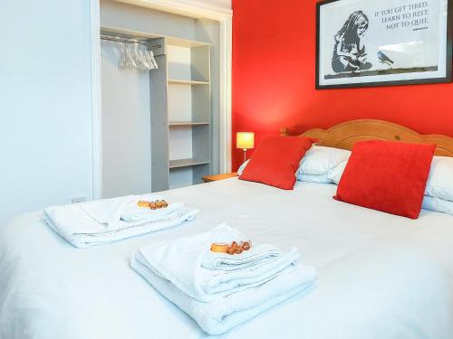 ein Schlafzimmer mit roten Wänden und ein Bett mit Handtüchern in der Unterkunft Bownessys Retreat - 26989 in Bowness-on-Windermere