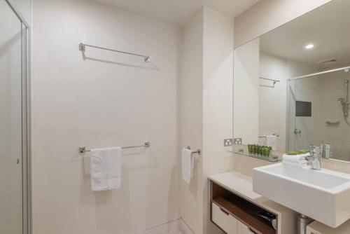 a white bathroom with a sink and a shower at 9309 Tranquil Viridian 2 Bedroom Luxury in Noosa Heads