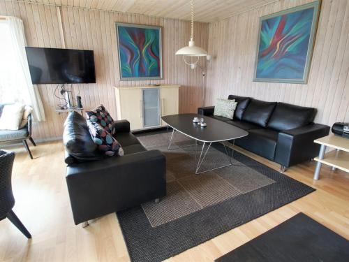 a living room with black leather furniture and a table at Holiday Home Svanhild - 1-2km from the sea in Western Jutland by Interhome in Fanø