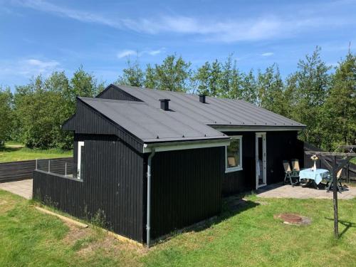 een zwarte schuur met een zwart dak in een tuin bij Holiday Home Patrice - 2km from the sea in Western Jutland by Interhome in Fanø