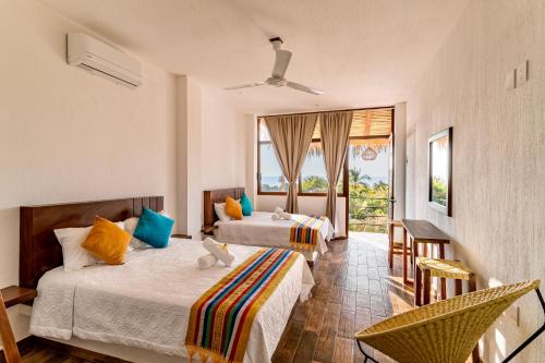 a hotel room with two beds and a balcony at Punta Kai Hotel Hostal in Puerto Escondido