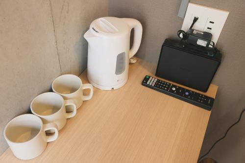 a table with three cups and a coffee maker on it at Hotel Tabiya in Tokyo