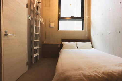 a small bedroom with a bed and a window at Hotel Tabiya in Tokyo