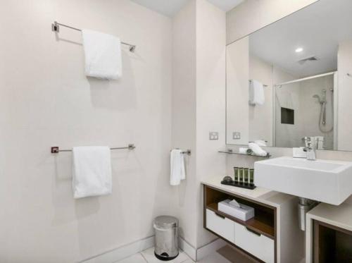 Baño blanco con lavabo y espejo en 7211 Lovely 2 Bedroom Viridian Noosa, en Noosa Heads