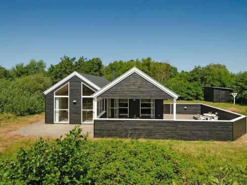 uma casa negra com um deque num campo em Holiday Home Erich - all inclusive - 1-8km from the sea by Interhome em Fanø