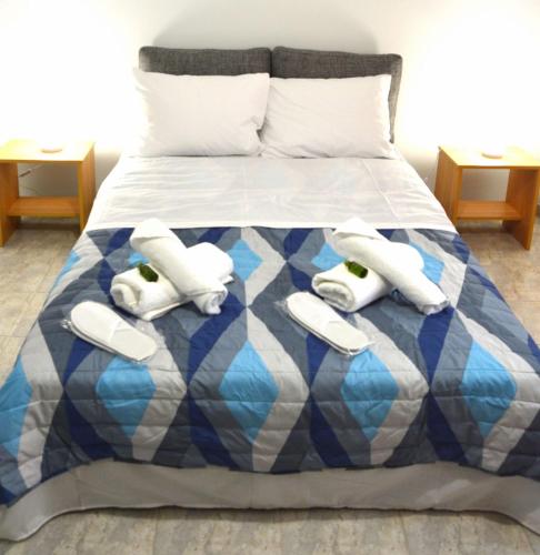 a bed with a blue and white comforter with three towels at EstellApartments in Athens
