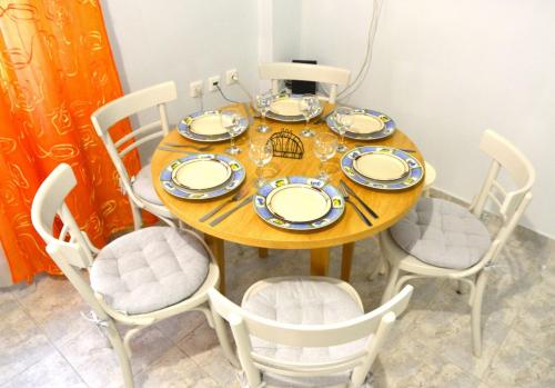 a wooden table with chairs and plates and glasses on it at EstellApartments in Athens