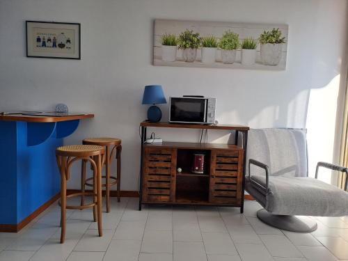 - un salon avec une télévision, une table et des chaises dans l'établissement Apartment in Residence BaiaSole, à Sanremo