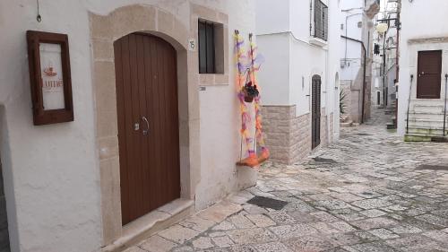 Une allée avec une porte marron sur le côté d'un bâtiment dans l'établissement Lumè, à Putignano