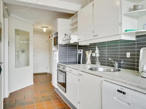 una cucina con armadi bianchi e lavandino di Apartment Iliane - 100m from the sea in Western Jutland by Interhome a Fanø