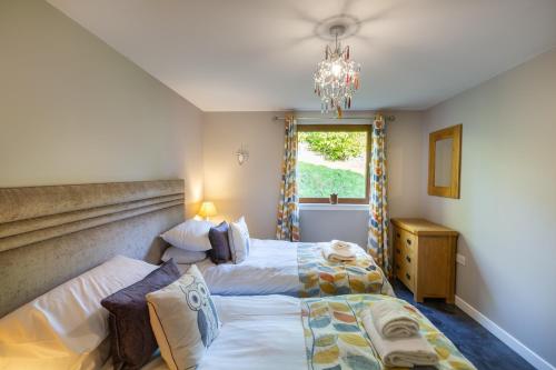 a bedroom with two beds and a chandelier at Lord Galloway 34 with Hot Tub in Newton Stewart