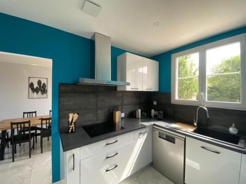 a kitchen with white cabinets and a blue wall at Maison cosy en plein coeur de Ouistreham in Ouistreham