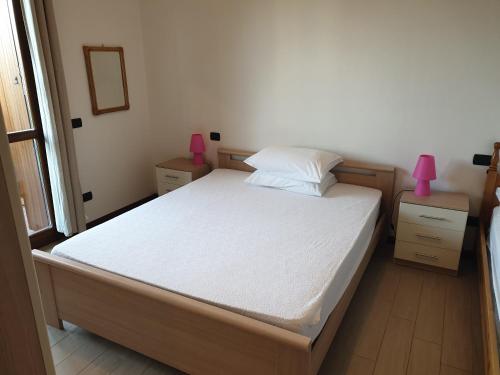 una camera da letto con un letto con lenzuola bianche e lampade rosa di CASA VACANZE DA RIKI a Peschiera del Garda