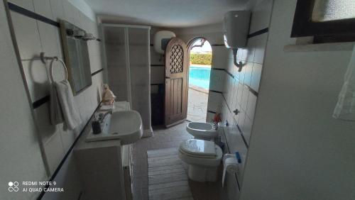 a bathroom with a toilet and a sink and a door at Villa con Piscina Privata fronte Spiaggia in Santa Marinella