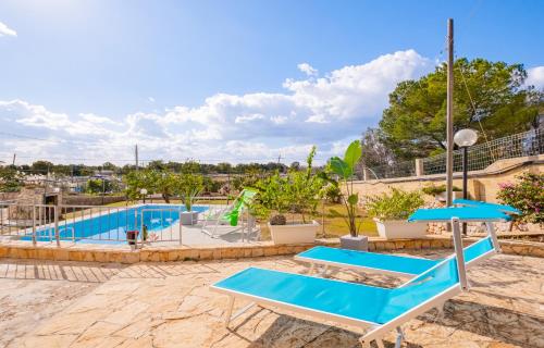 a swimming pool with blue tables and umbrellas at Villa Le Fontanelle - Torre San Giovanni by HDSalento in Torre San Giovanni Ugento