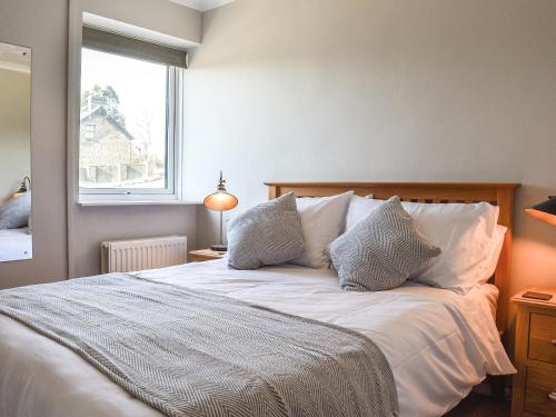 um quarto com uma cama branca com almofadas e uma janela em Meadow Cottage em Gowerton