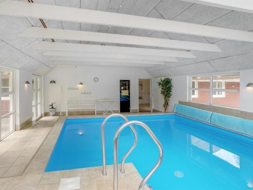 a large swimming pool with blue water in a building at Holiday Home Jenna - 1-4km from the sea in Western Jutland in Vesterhede