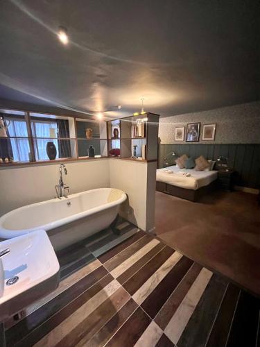 a large bathroom with a tub and a bed at The Ostrich Inn Colnbrook London Heathrow in Slough