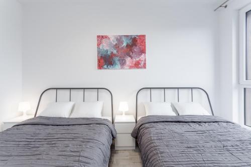 two beds in a bedroom with a painting on the wall at Chill Apartments Airport Ursynów in Warsaw