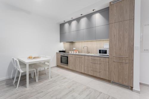 a kitchen with wooden cabinets and a white table at Chill Apartments Airport Ursynów in Warsaw