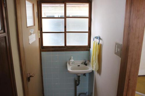 a bathroom with a sink and a window at Minshuku Katsuya in Shirahama