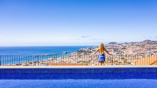 kobieta w niebieskiej sukience stojąca na krawędzi basenu w obiekcie Casa da Pinheira 2 w Funchal