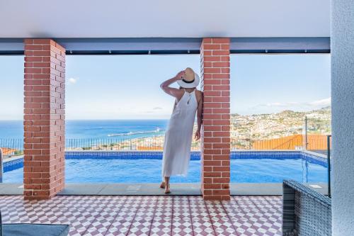 a woman in a white dress and hat leaning against a wall at Casa da Pinheira II - By Wehost in Funchal
