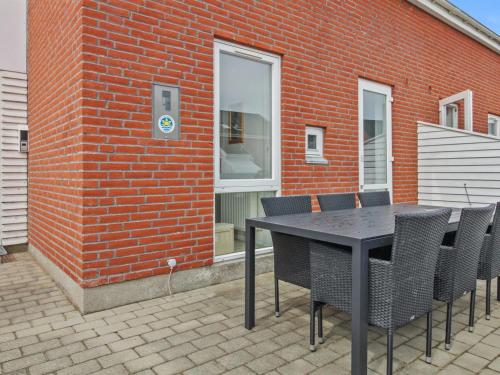 een zwarte tafel en stoelen voor een bakstenen gebouw bij Apartment Raine - 2-3km from the sea in Western Jutland by Interhome in Sønderby