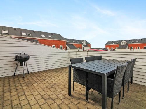 een patio met een tafel en stoelen en een grill bij Apartment Raine - 2-3km from the sea in Western Jutland by Interhome in Sønderby