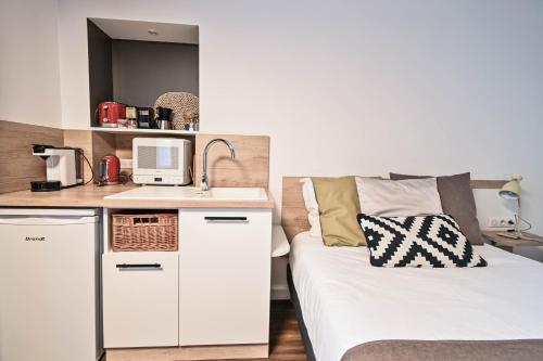 a small bedroom with a bed and a kitchen at Les cles du 27 Paris in Paris